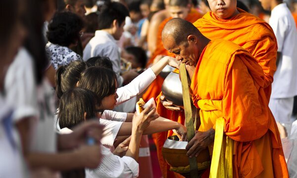 Giving alms to monks in Thailand.