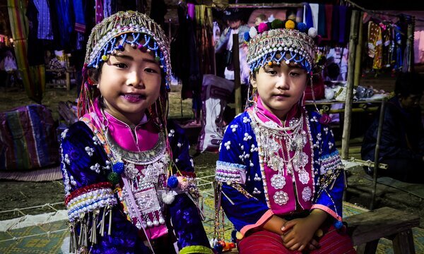 Two hill tribe girls wearing traditional clothing in Thailand.