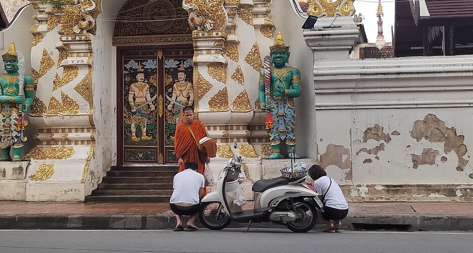 Monks receiving alms from locals by the roadside