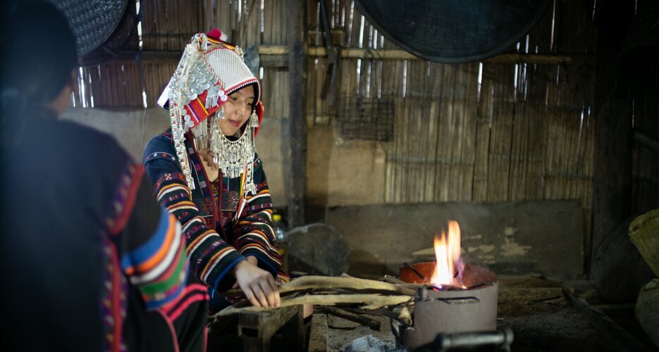 Akha girl lighting a wood fire
