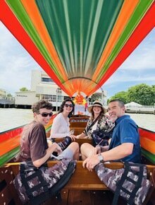 A family explores Bangkok's local waterways on a traditional longtail boat.
