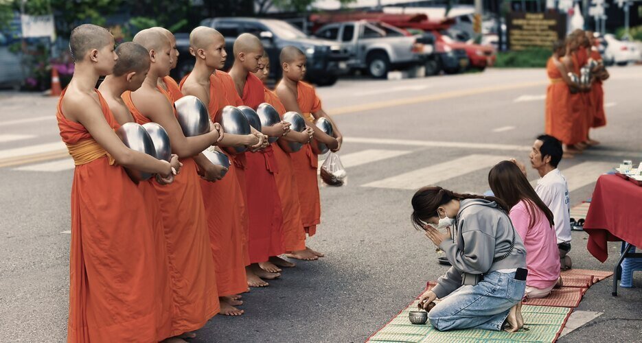 Monks receiving alms from locals by the roadside